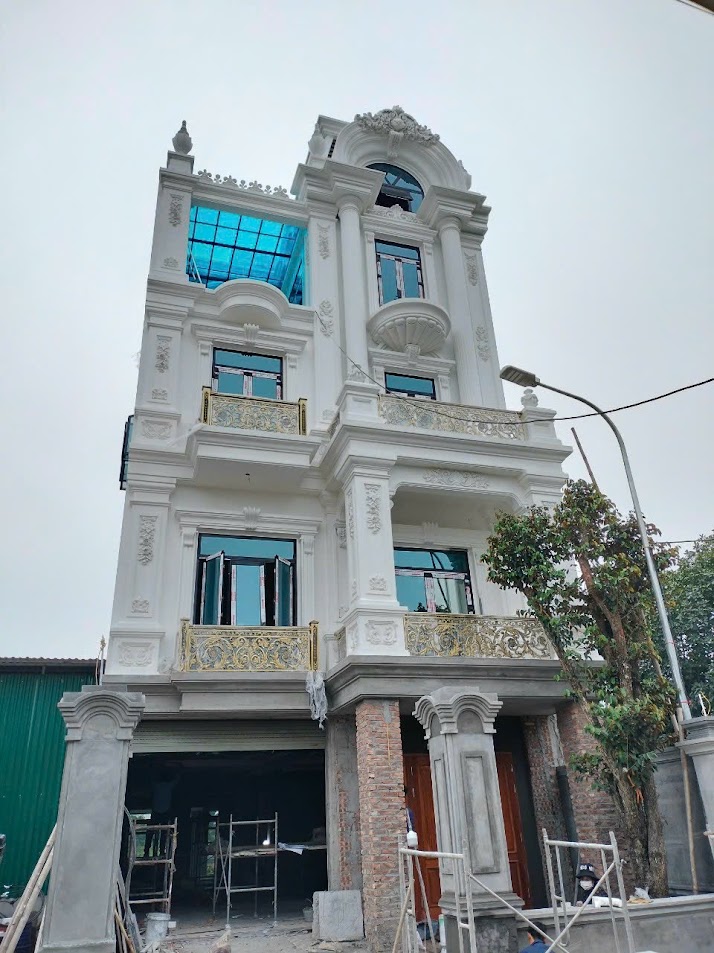 Nhà phố tân cổ điển 4 tầng màu trắng đang thi công với ban công lan can sắt nghệ thuật mạ vàng